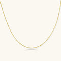 Delicate 14K gold-plated box chain necklace with evenly spaced bar links, shown flat on cream background.